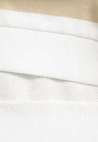 Strati di tessuto bianco con texture a coste e rete, con una sezione liscia color beige sopra. Design pulito e semplice senza motivi.