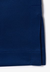 Tela azul marino con una textura suave, que presenta una abertura lateral y detalles de costura fina. Diseño sencillo con un acabado limpio.