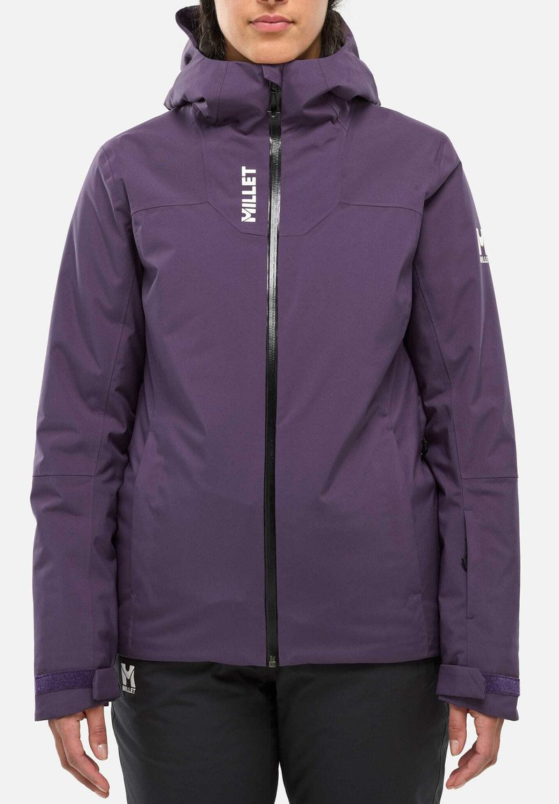 Person wearing a purple hooded winter jacket with front zipper and black pants, standing against a plain white background.