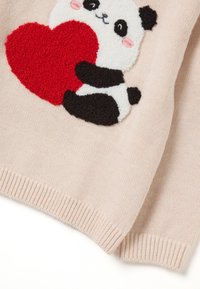 Gebreide trui met een getextureerde panda die een groot rood hart omarmt op een zachte roze achtergrond.