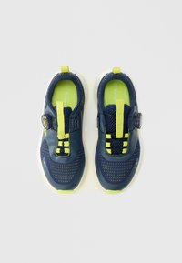 Chaussures bleu marine et vert citron avec une tige en mesh, une semelle en caoutchouc et un système de fermeture à molette. Semelle blanche épaisse avec motifs texturés.