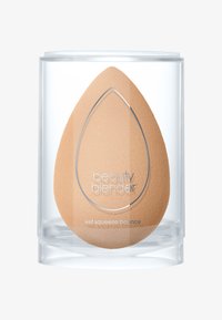 Beauty Blender spons in een doorzichtige container. De spons heeft een druppelvorm, is zacht en mat in een lichte beige kleur, met ingegoten branding.