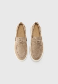Beige velúrbőr slip-on cipők lekerekített orral, fűzős díszítéssel és fehér gumitalppal. Texturált felület és logó a talp bélésén.