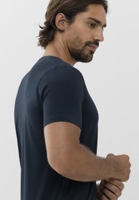 Námořnická modrá tričko s krátkým rukávem a kulatým výstřihem, vyrobené z měkké látky. Má klasický střih a minimální švy pro čistý vzhled.