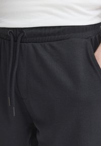 Mustad puuvillased jookspüksid elastse vöörihma ja nööriga. Omavad küljetaskuid ja sujuvat tekstuuri. Minimalistlik disain.