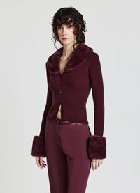 Burgunderfarbener, gerippter Cardigan mit einem Kragen und Manschetten aus Kunstfell, der über ein tailliertes Design und eine Knopfleiste verfügt. Glatte, weiche Textur.