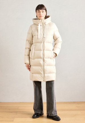 Beige pufferjack met een getailleerde taille, volledige rits en verstelbare capuchon. Heeft horizontale quiltstructuur en zijzakken.