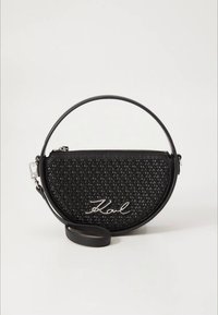 Rund sort taske med vævet tekstur, sølv lynlås og skulderrem. "Karl" logo i sølv er tydeligt fremhævet på fronten.