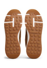 Semelles de baskets en caoutchouc marron avec un motif en texture carrée et la marque "Tommy Hilfiger" visible au centre.