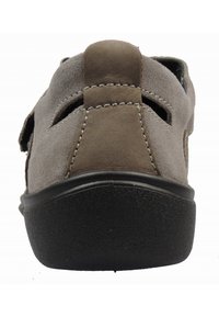 Světle hnědá semišová zadní část boty s texturovanou černou gumovou podrážkou, která má prořezávané vzory a švy podél švu.