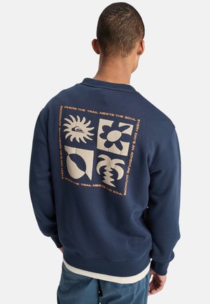 Marineblauwe sweatshrit gemaakt van zachte stof, met een grote grafische print in roomkleur op de achterkant met geometrische en door de natuur geïnspireerde ontwerpen.