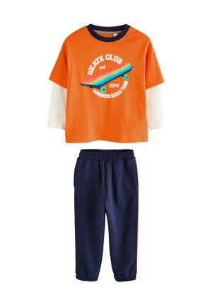 Orange t-shirt med korte ærmer og skategrafik samt marineblå sweatpants med orange sidekanter, lavet af blødt bomuldsblandingsmateriale.