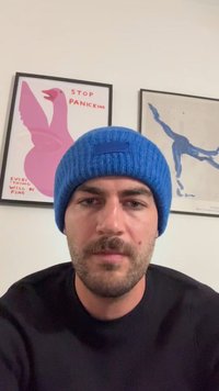 Cappello a maglia blu con un motivo trapuntato e una piccola toppa. Maglione nero. Art decorativa con illustrazioni di uccelli rosa e blu.