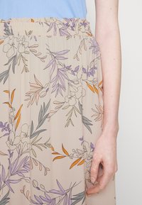Jupe à imprimé floral en beige clair avec des accents de violet, d'orange et de vert ; possède une taille élastique et une texture fluide.