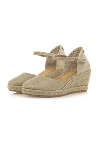 Espadrilles de cuña en color beige claro con correa. Parte superior de tela texturizada y trenzada. Suela de yute trenzado y plantilla suave con patrón de hojas.