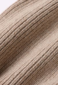 Beige knitted fabric with vertical ribbed texture. Soft, fuzzy material features alternating thin and thick lines. No notable patterns or accents.