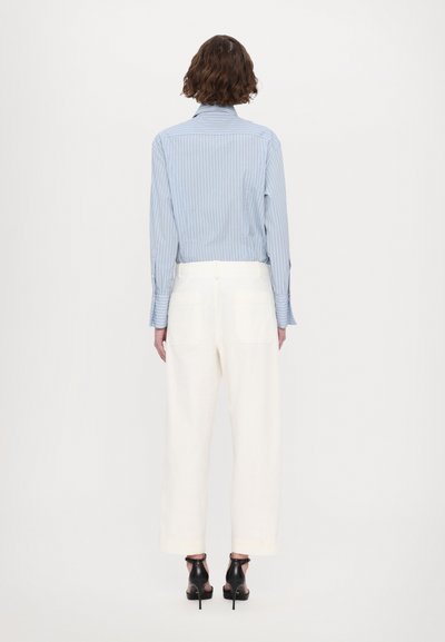 Blue and white striped button-up shirt paired with white wide-leg pants and black high-heeled sandals, viewed from behind.