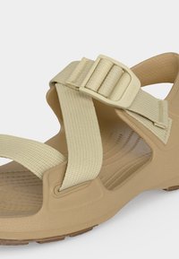 Μπεζ σανδάλι με ανοιχτά δάχτυλα, ρυθμιζόμενους υφασμάτινους ιμάντες και πλαστική αγκράφα πάνω σε υφασμένη επενδεδυμένη σόλα.