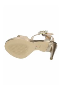 Sandalo con tacco alto in pelle laccata beige, con suola testurizzata, cinturino decorato con gemme e dettaglio a fiocco sul retro.