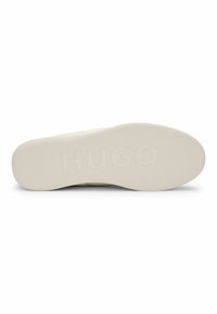 Valkoinen kumisohva, jossa on teksturoitu pinta, jossa on kohokuvioitu 'HUGO' logo. Tasainen muotoilu vakauden ja pidon takaamiseksi.