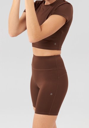 Brown athletic crop top and high-waisted shorts made of smooth fabric. Features include short sleeves and a small logo on the hem.