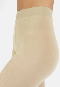 Leggings beige con una consistenza liscia e elastica e una ampia vita a coste, caratterizzati da un design senza cuciture per il massimo comfort e una finitura pulita.