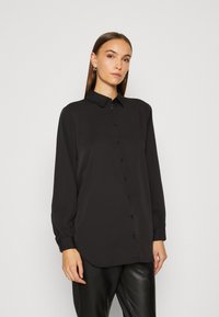 Black button-up shirt with long sleeves, featuring a smooth fabric, rounded hem, and subtle button accents along the front.