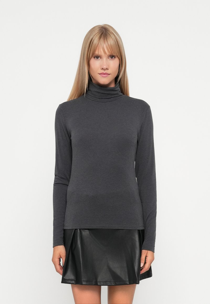 Sivi turtleneck s dugim rukavima, uskog kroja, izrađen od meke, rastezljive tkanine; kombiniran s crnom suknjom od umjetne kože s proširenim krojem.