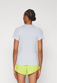 Vaaleansininen lyhythihainen t-paita, jossa on pyöreä kaula-aukko ja raglan-hihat, yhdistettynä kirkkaan neonvihreisiin shortseihin, jotka ovat sileäpintaiset.