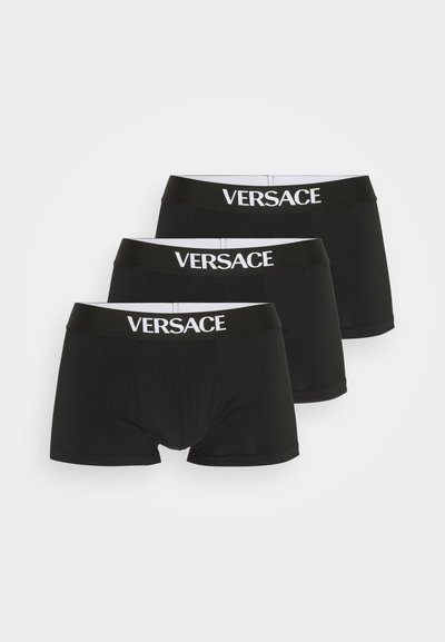 Schwarze Baumwollboxershorts mit einem weißen "VERSACE"-Logo auf dem elastischen Bund. Drei Einheiten in gestapelter Formation präsentiert.