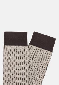 Adītas zeķes ar beigu tonī bāzi, melniem diagonāliem svītrainiem un tumši brūnu ribotu apkakli, ar teksturētu apdari.