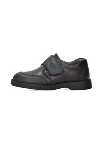 Zapato de cuero negro con una correa de velcro, punta redonda, superficie texturizada y suela baja de goma. Adecuado para un uso casual o formal.