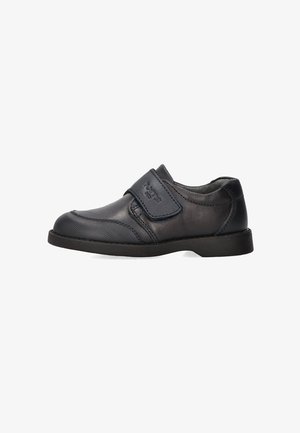 Zapato de cuero negro con una correa de velcro, punta redonda, superficie texturizada y suela baja de goma. Adecuado para un uso casual o formal.