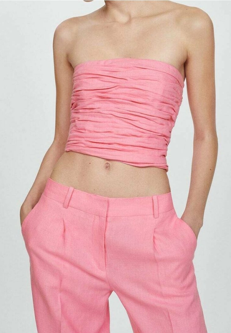 Top sin tirantes con textura fruncida en rosa claro, combinado con pantalones de lino a medida en el mismo tono, que cuentan con bolsillos laterales y un acabado suave.