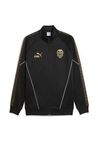 Svart zip-up jacka med guldaccent, med en logotyp och ordet "KING" i guld. Sidopanelerna har geometriska mönster. Vita kantdetaljer.