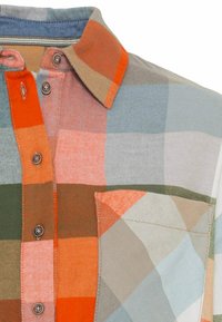 Chemise à carreaux bleu, orange, vert et beige. Dotée d'un col, d'une poche avant et de boutons arrondis sur un tissu texturé.