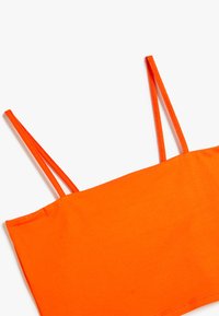 Lys orange cropped top med tynde stropper. Lavet af glat stof, med et enkelt, tætsiddende design uden yderligere mønstre.