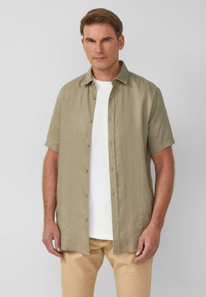 Korte mouwen, button-down overhemd van licht olijfgroen linnen, met een kraag en een relaxed fit, gedragen over een wit T-shirt.