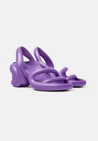 Violetti flip-flop-sandaalit, jotka on valmistettu joustavasta kumista, joissa on muotoillut hihnat ja pehmeä pohja sileällä pinnalla.