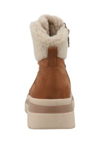 Brune suedestøvle med en cremefarvet faux fur-krave, fremhævet lynlås lukning og en struktureret hvid sål. Bagsiden viser hældesignet.