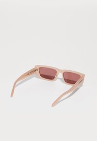 Ochelari de soare roz cu rame pătrate, din material plastic transparent, cu lentile de culoare roșie și un detaliu din metal la balama.