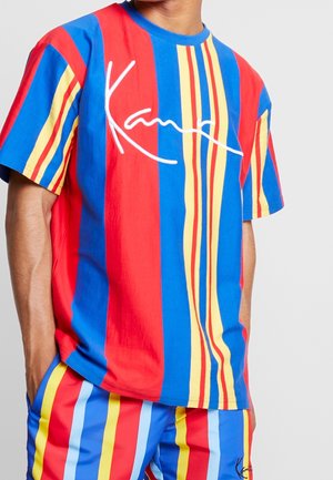 Koszulka z krótkim rękawem w pionowe paski w kolorach czerwonym, niebieskim i żółtym; posiada biały napis logo; wykonana z miękkiego, oddychającego materiału.