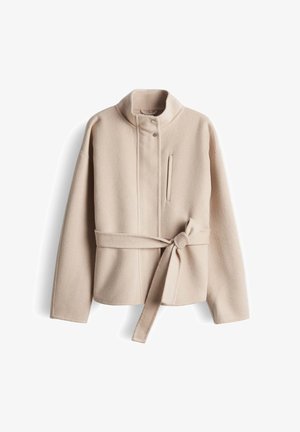 Beige fleecejack met een hoge kraag, knoopsluiting aan de voorkant, een horizontale zak en een tailleceintuur met strik. Zachte textuur en een ontspannen pasvorm.