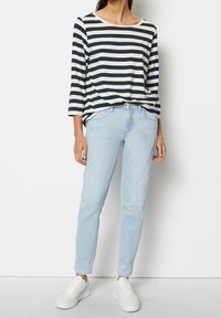 Randig långärmad topp i marinblå och krämfärg, matchad med ljusblå jeans och vita sneakers. Enkel, avslappnad passform med rundad halsringning.