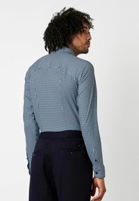 Langärmliges Hemd mit einem blau-weißen Karomuster, ausgestattet mit einem strukturierten Kragen und knöpfbaren Manschetten, kombiniert mit dunklen Hosen.