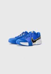 Blaue sportliche Sneakers mit Mesh-Obermaterial, gelben Akzenten und schwarzem Nike-Logo. Verfügt über eine strukturierte Sohle und einen gepolsterten Schaft für zusätzlichen Komfort.