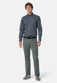 Camicia a scacchi blu navy con dettagli verdi, abbinata a pantaloni verde chiaro e scarpe grigie. Vestibilità dritta con colletto a bottoni.