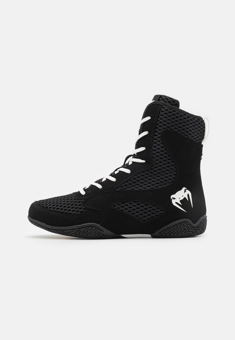 Schwarze High-Top-Schuhe mit Mesh-Einsätzen, weißen Schnürsenkeln und einem auffälligen Logo. Die strukturierte schwarze Sohle hat ein Zickzackmuster für besseren Halt.