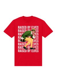 Červené tričko s opakujícím se bílým nápisem „Raised by Elves“ a skrčujícím se mužem oblečeným jako zelený a žlutý skřítek s zakroucenými botami.