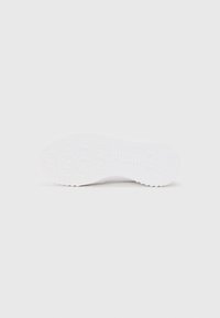 White sneaker sole with a textured pattern, featuring hexagonal shapes and grooves for traction. Smooth rubber material.